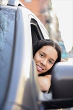 Portrait of Hispanic woman leaning out car window