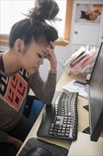 Frustrated Mixed Race woman sitting at desk using computer