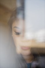 Face of pensive Mixed Race woman behind window