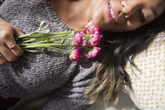 Mixed Race woman laying on bed holding flowers