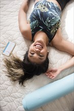 Smiling Mixed Race woman laying on bed resting after workout
