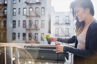 Mixed Race woman planting flowers in rooftop planter