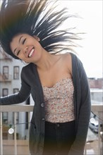 Mixed Race woman tossing hair on rooftop