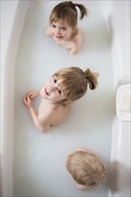 Caucasian boy and girls looking up in bathtub