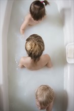 Caucasian boy and girls sitting in bathtub