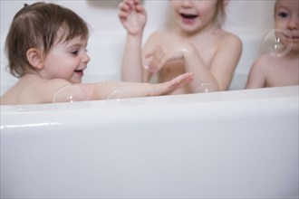 Smiling Caucasian boy and girls playing in bathtub