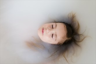 Face of Caucasian girl floating in bathtub