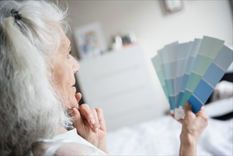 Pensive older woman examining color swatches