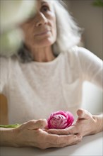 Older woman holding pink flower
