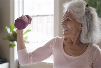 Smiling older woman lifting weights