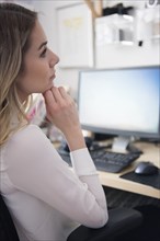 Pensive Caucasian woman sitting at computer desk