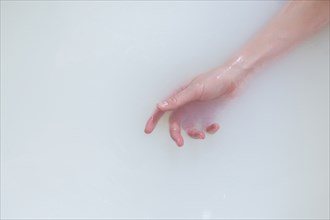 Hand of Caucasian woman in the milk bath