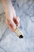 Hand of Caucasian woman holding a ritual incense