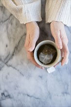 Hands of Caucasian woman holding cup of tea