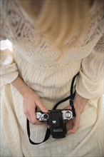 Hands of Caucasian woman holding camera in lap