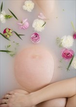 Caucasian expectant mother in milk bath with flowers