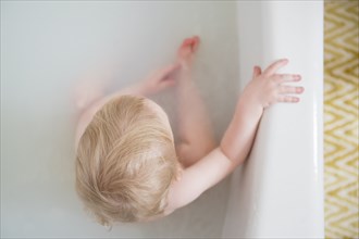 Caucasian baby boy in milk bath