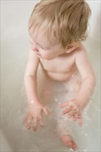 Caucasian baby boy splashing in milk bath