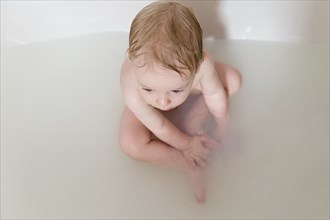 Caucasian baby boy sitting in bathtub
