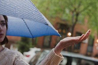 Caucasian woman holding umbrella checking rain