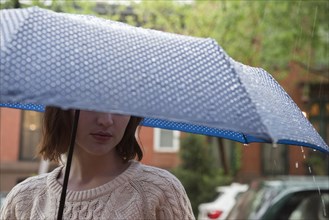 Caucasian woman holding an umbrella in rain