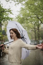 Carefree Caucasian woman holding an umbrella in the rain