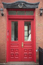 Caucasian woman daydreaming behind red door