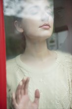 Caucasian woman daydreaming behind foggy window