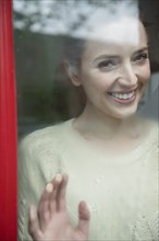 Caucasian woman smiling behind foggy window