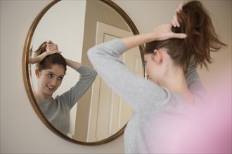 Reflection of Caucasian woman in mirror pulling back hair