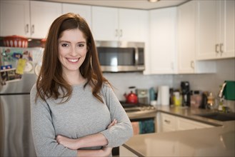 Portrait of smiling Caucasian woman standing in domestic kitchen