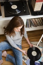 Caucasian woman sitting on floor examining vinyl record