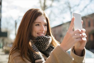 Caucasian woman wearing scarf posing for cell phone selfie
