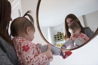 Reflection of Caucasian mother and baby daughter in mirror