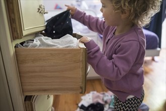 Caucasian girl removing clothing from dresser drawer
