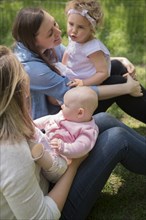 Caucasian mothers and daughters sitting in grass