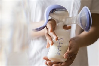 African American woman holding milk in breast pump
