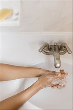 African American woman washing hands with soap