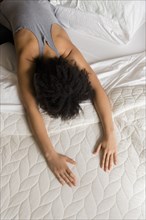 African American woman stretching back on bed