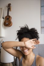 Smiling African American woman covering eyes with arm