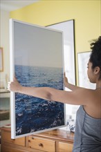 African American woman admiring large photograph of ocean