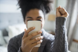 African American woman celebrating while texting on cell phone