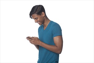 Smiling Hispanic man text messaging on cell phone