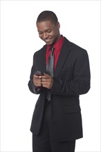 Smiling businessman text messaging on cell phone