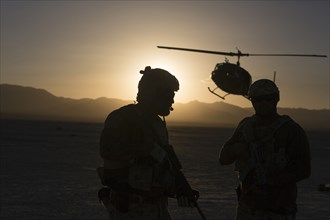 Silhouette of soldiers and helicopter in desert landscape