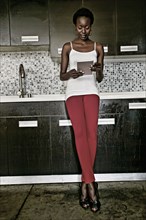 Black woman using digital tablet in kitchen
