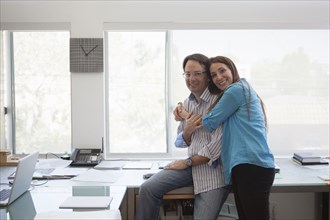 Smiling couple hugging in home office