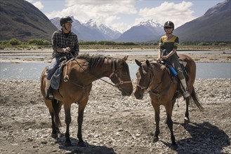 Caucasian couple horseback riding near river