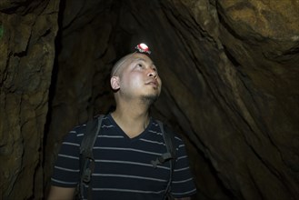 Chinese man wearing headlamp in cave