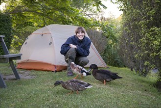 Smiling Caucasian woman camping near ducks